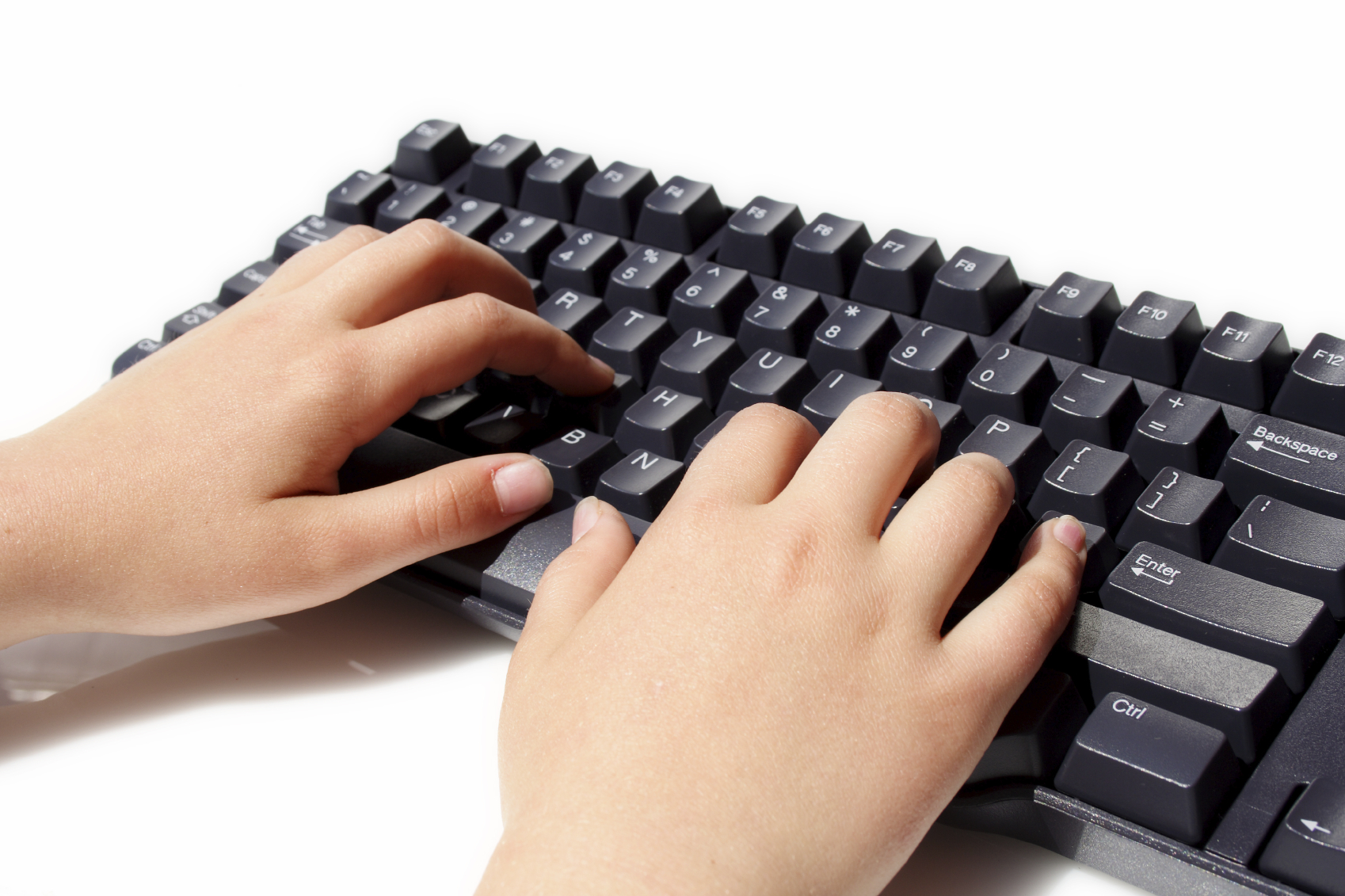 Close-up of a person's hands typing at a computer keyboard in an office setting.
