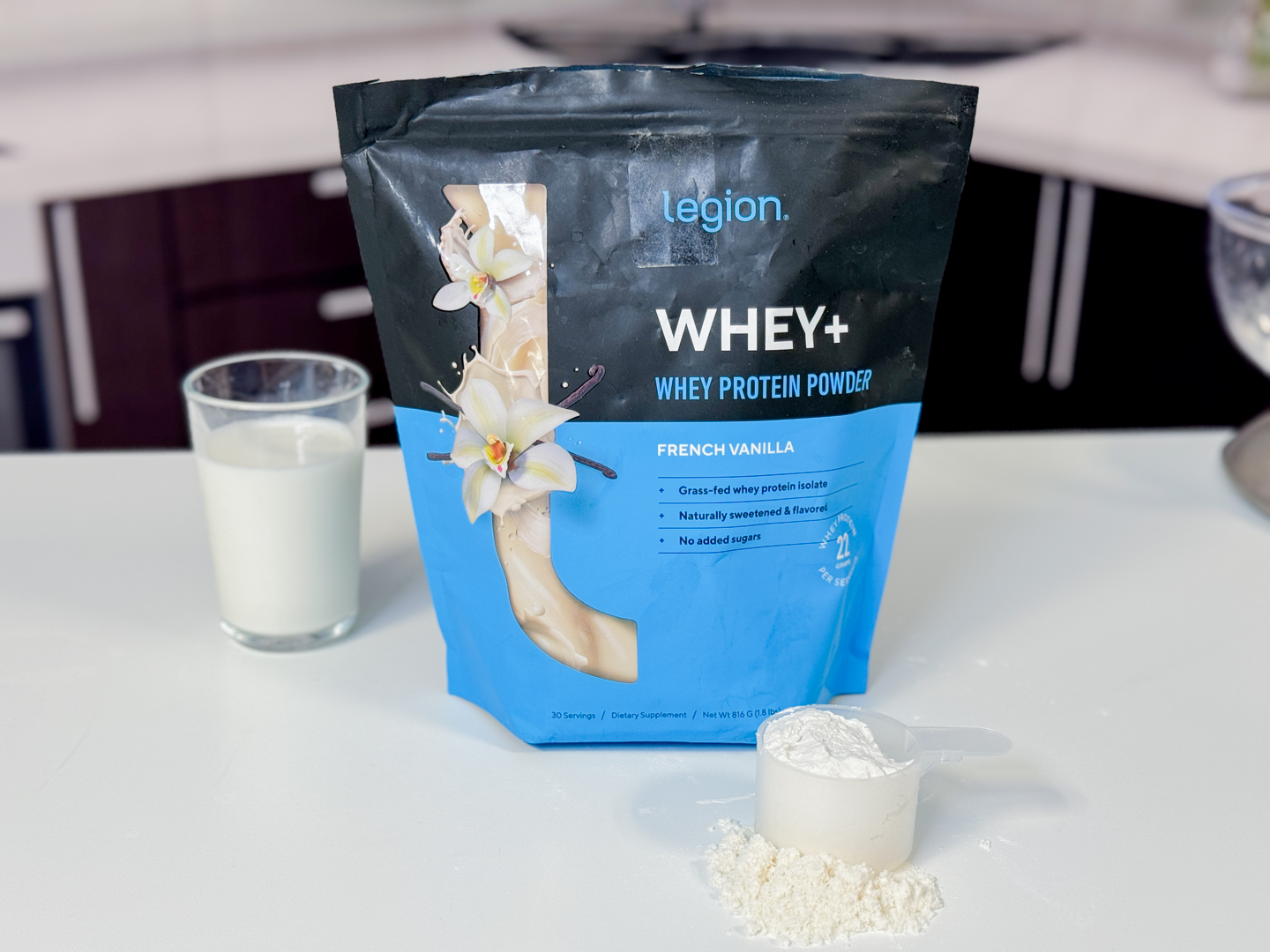 A person holding a container of Legion Whey+ protein powder to evaluate the label.