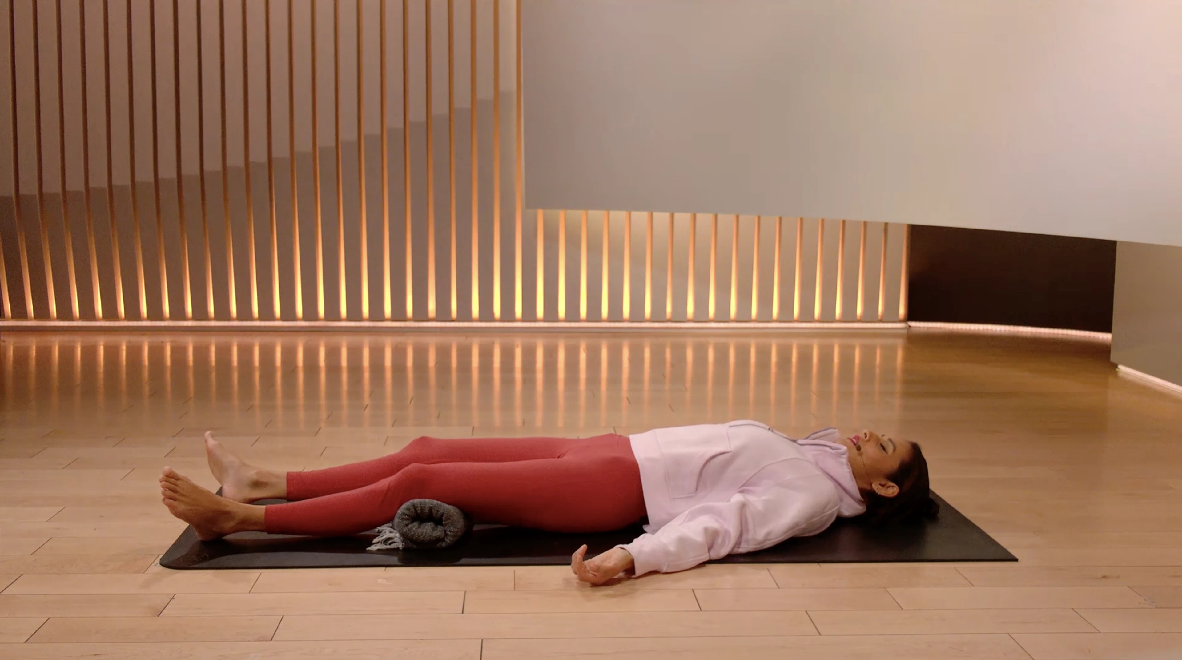 Aditi Shah lying flat on her back in Savasana or Corpse Pose.