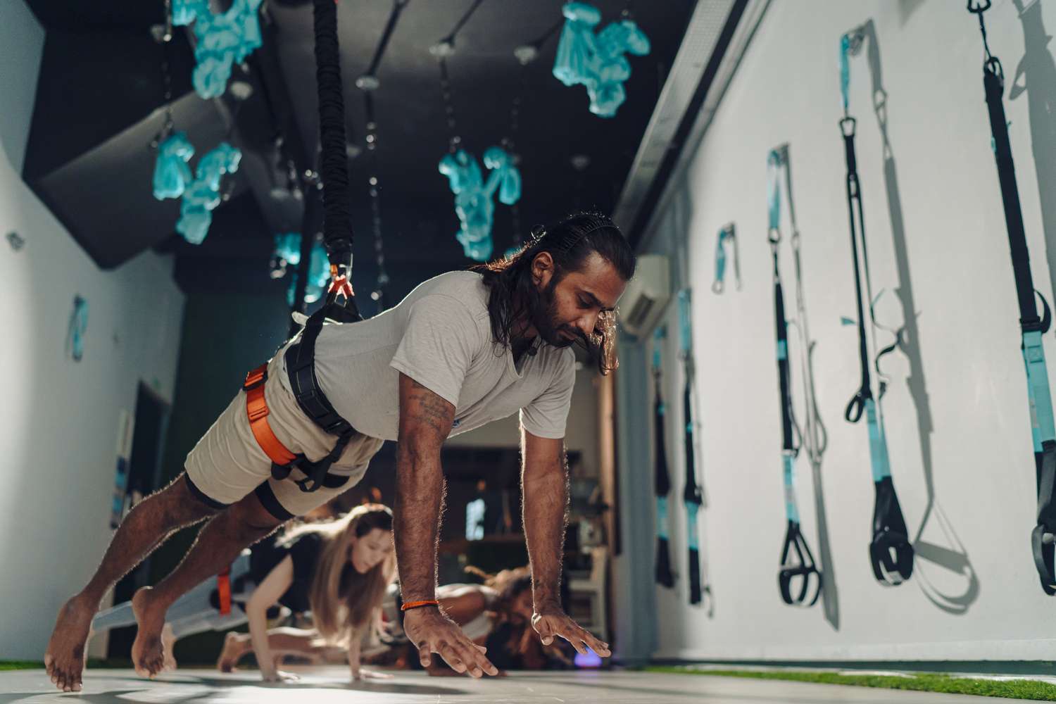 A fitness enthusiast performing a suspended plank in a professional studio setting