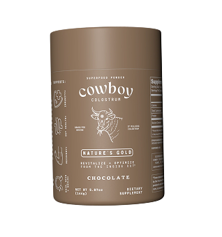 Cowboy Colostrum powder being stirred into a glass of liquid.