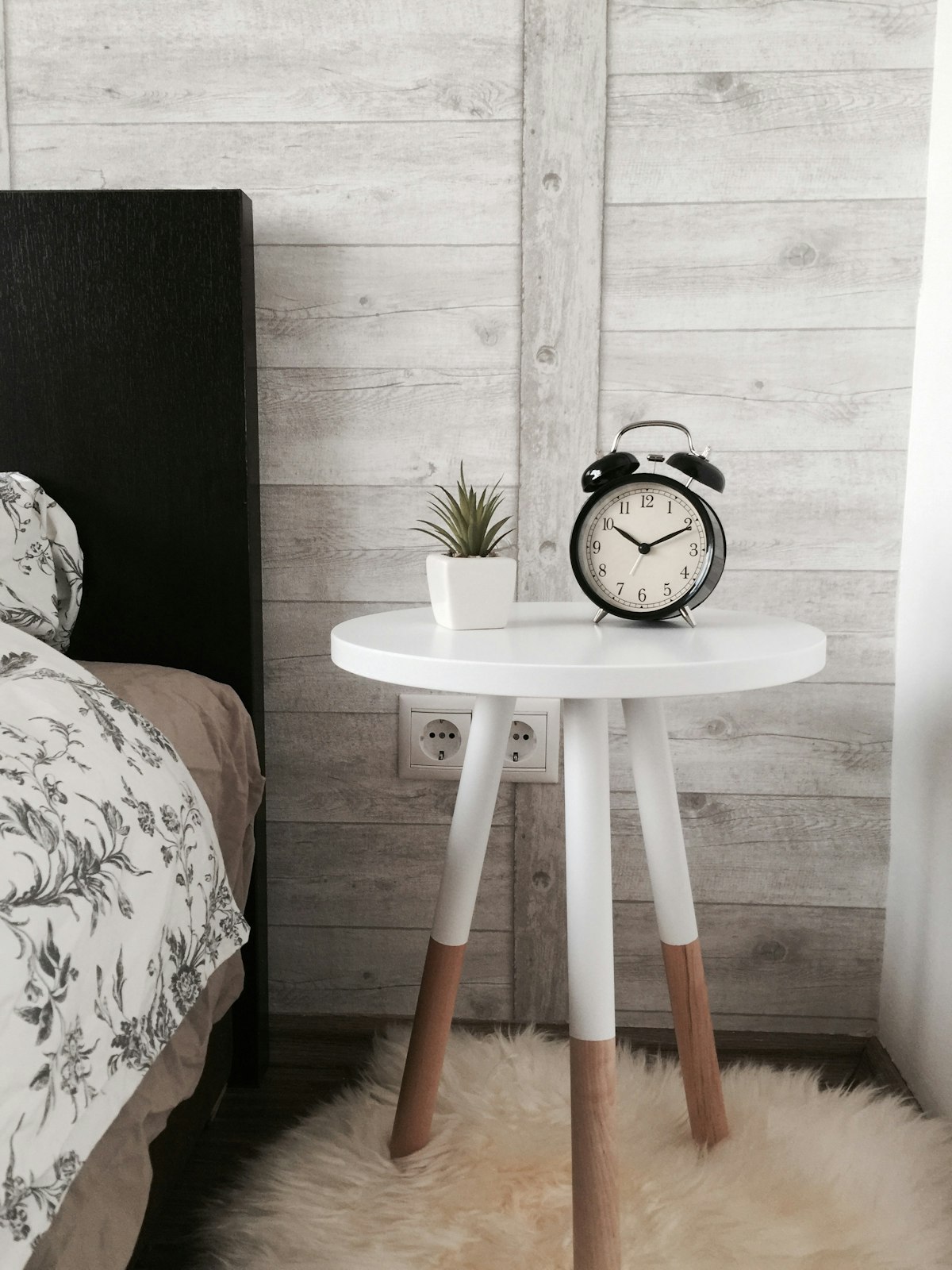 A person sitting on the edge of a bed in a bedroom, holding their hands to represent morning joint stiffness.