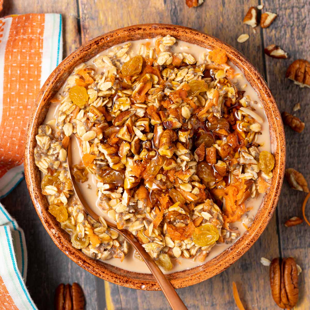 A bowl of carrot cake inspired overnight oats topped with shredded carrots and walnuts.