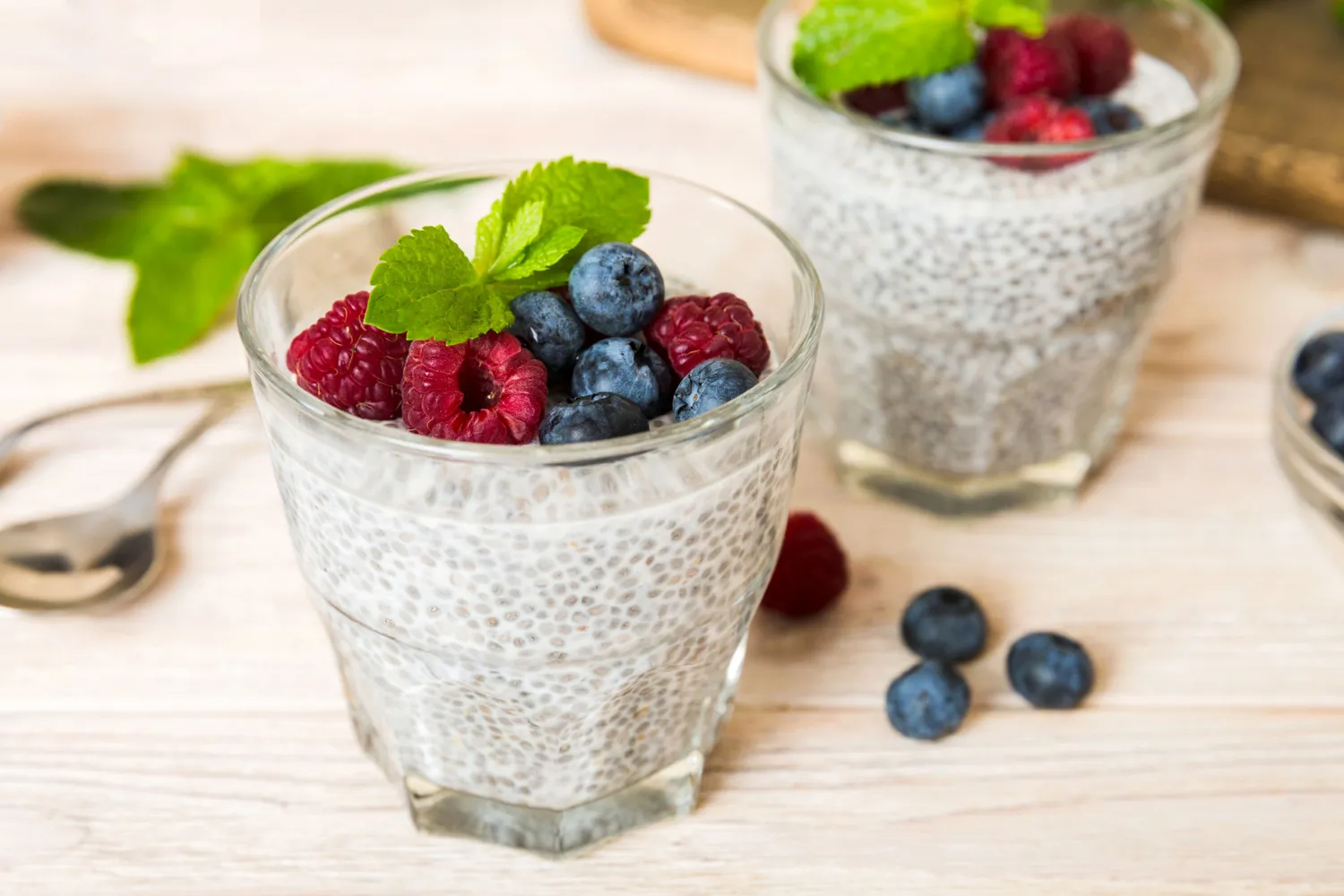 A glass of chia seed pudding topped with fresh blueberries.