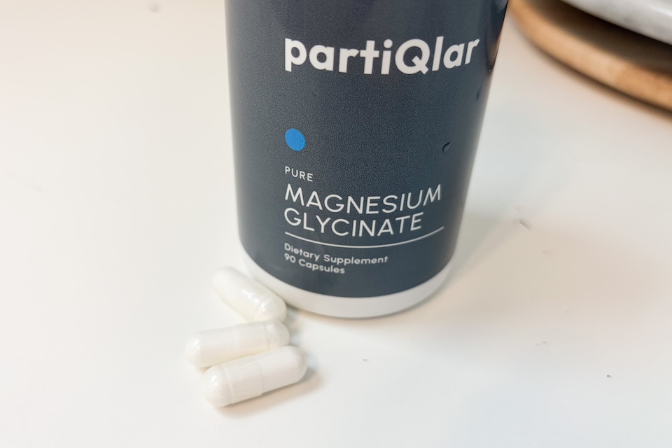 PartiQlar Magnesium Glycinate bottle with capsules scattered on a surface.