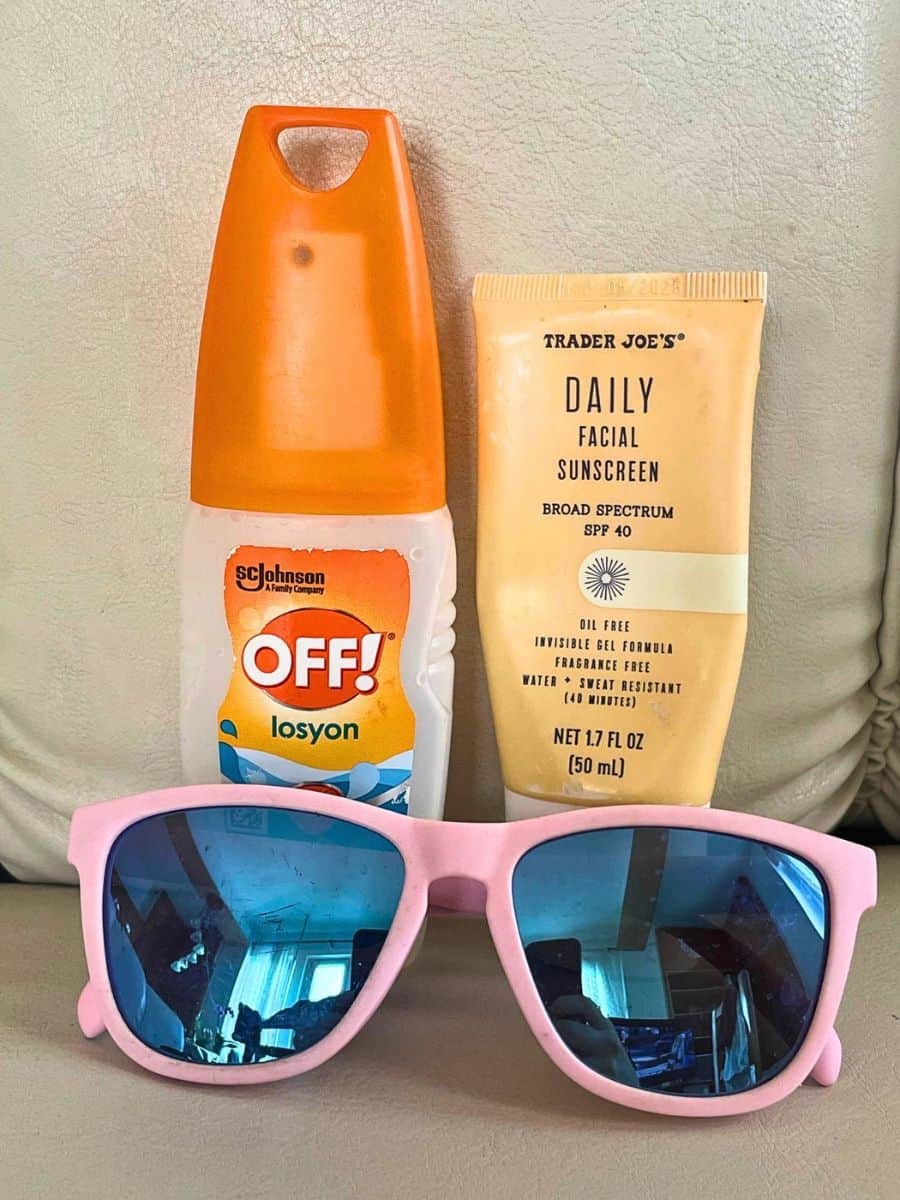 Travel essentials including sunglasses, sunscreen, and skincare items laid out for a trip.