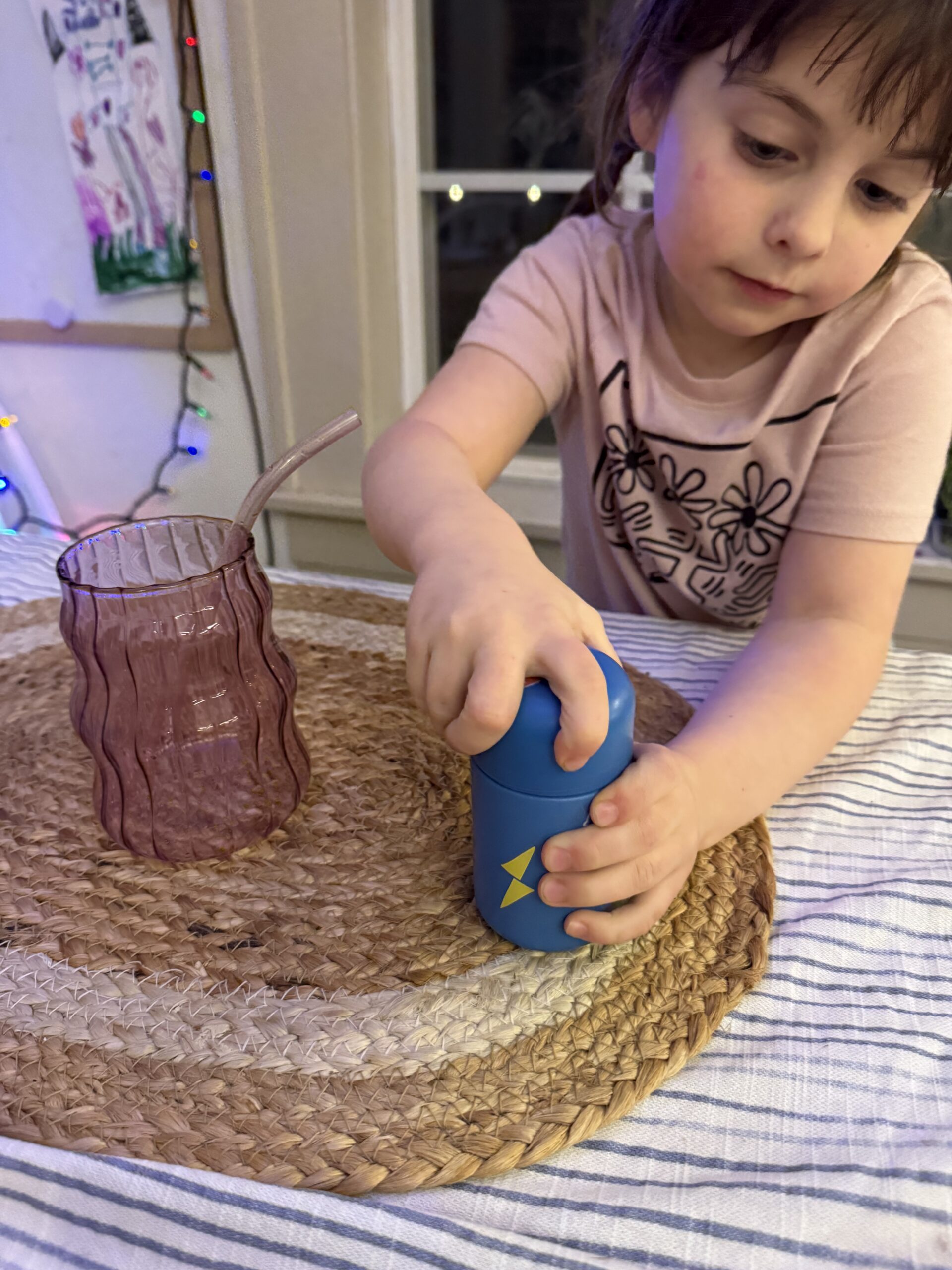 A young child's hands opening a yellow Hiya refillable multivitamin bottle.