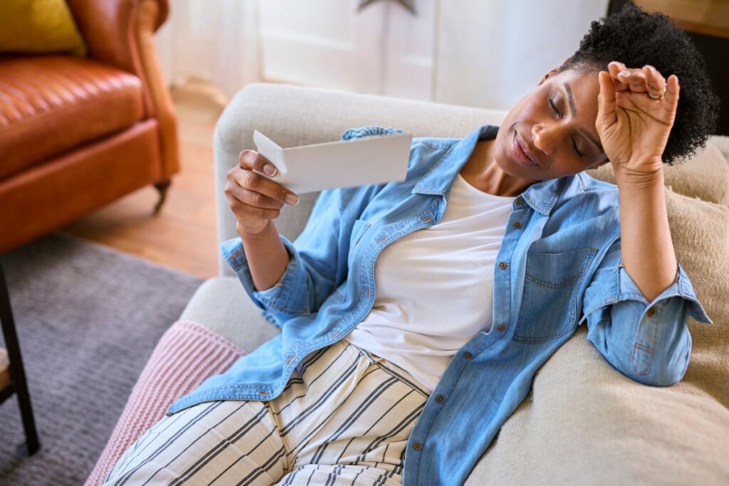 A woman in an office setting fanning herself with her hand while appearing flushed.