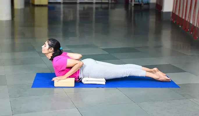 A person practicing Cobra Pose (Bhujangasana) supported by yoga blocks.