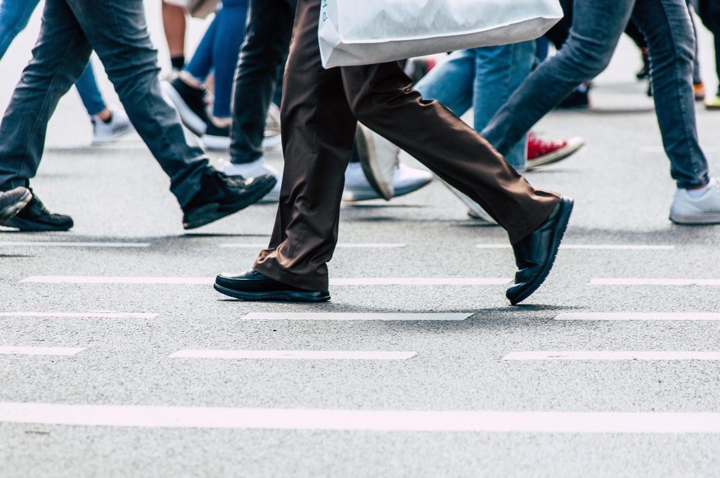 A pedestrian walking in a town representing the struggle of maintaining a busy lifestyle while fatigued.