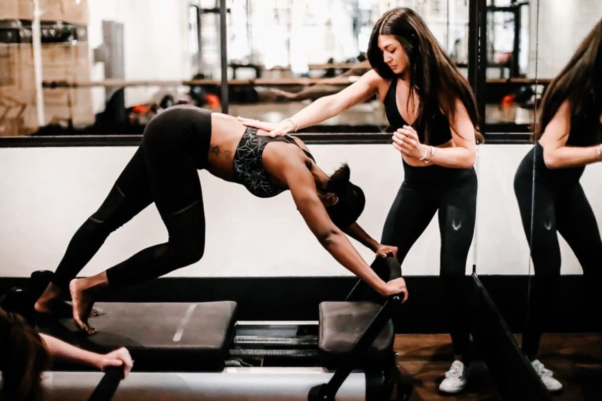 Wide shot of an atmospheric Heartcore Pilates studio featuring rows of reformer machines under warm lighting.