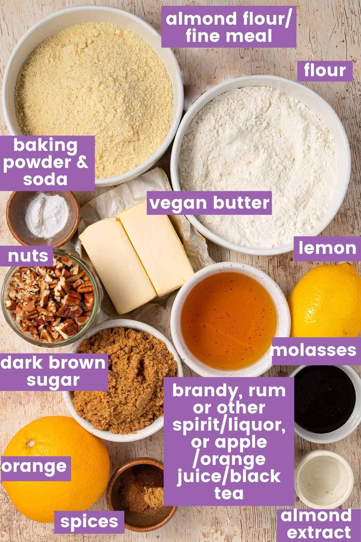Various vegan Christmas cake ingredients including dried fruits, spices, and molasses on a table.