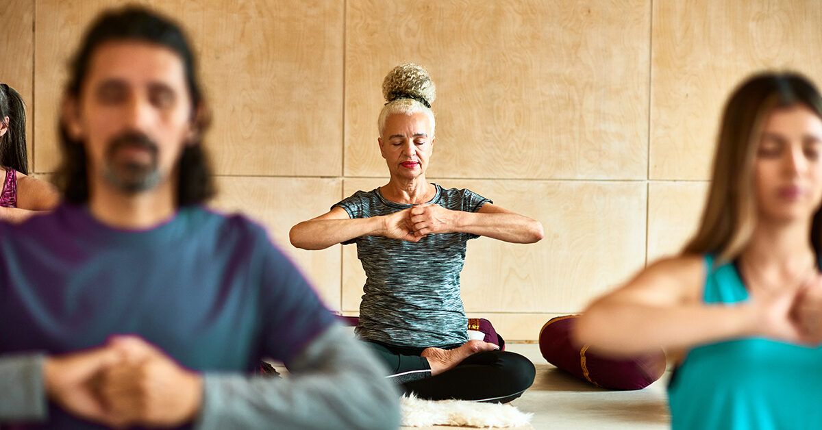 A diverse group of adults practicing seated meditation and mindfulness in a professional yoga studio.