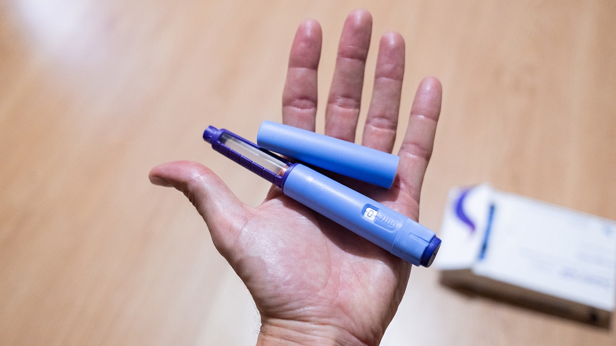 Hand holding GLP-1 injection pens used for medical weight loss.