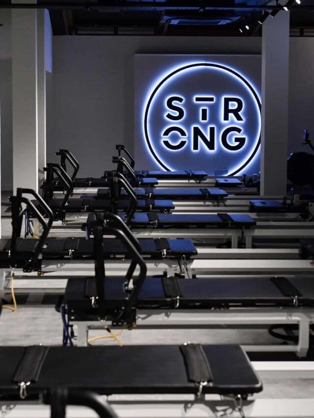 A modern fitness studio setup featuring a row of Strong Pilates machines combining reformers with rowing components.