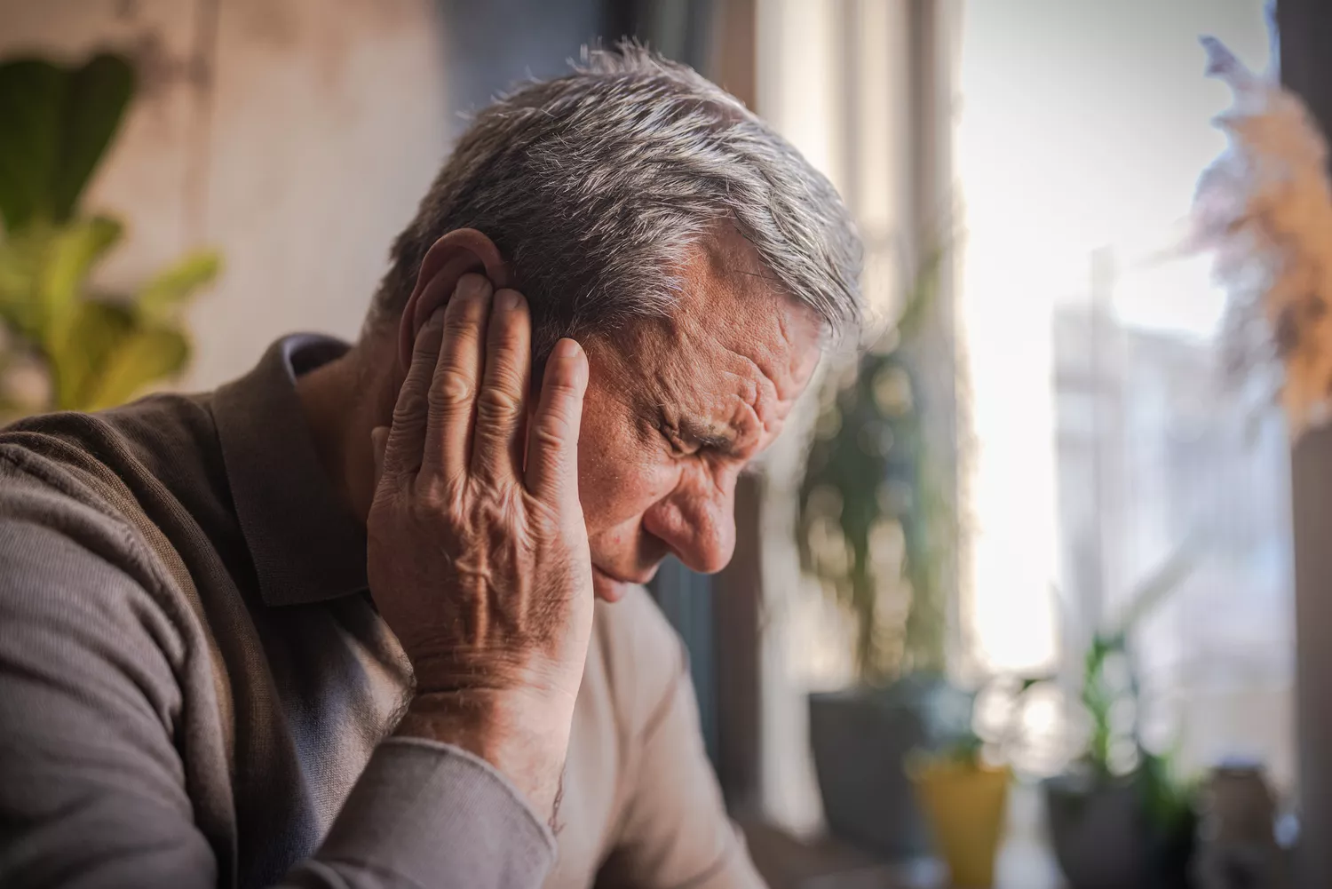 A man holding the side of his neck in discomfort, illustrating common cervical strain from poor posture.