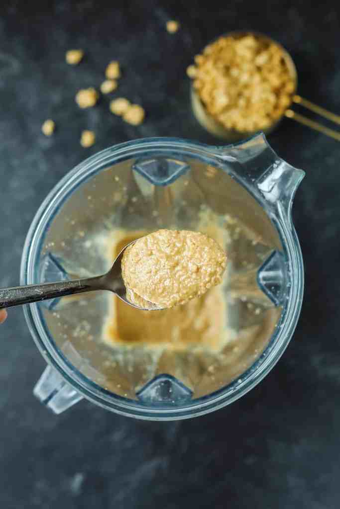 A bowl of dry rolled oats next to a small jar of melted coconut oil.