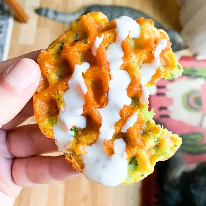 A thick, fluffy broccoli and cheddar waffle served with a side of creamy ranch dressing.