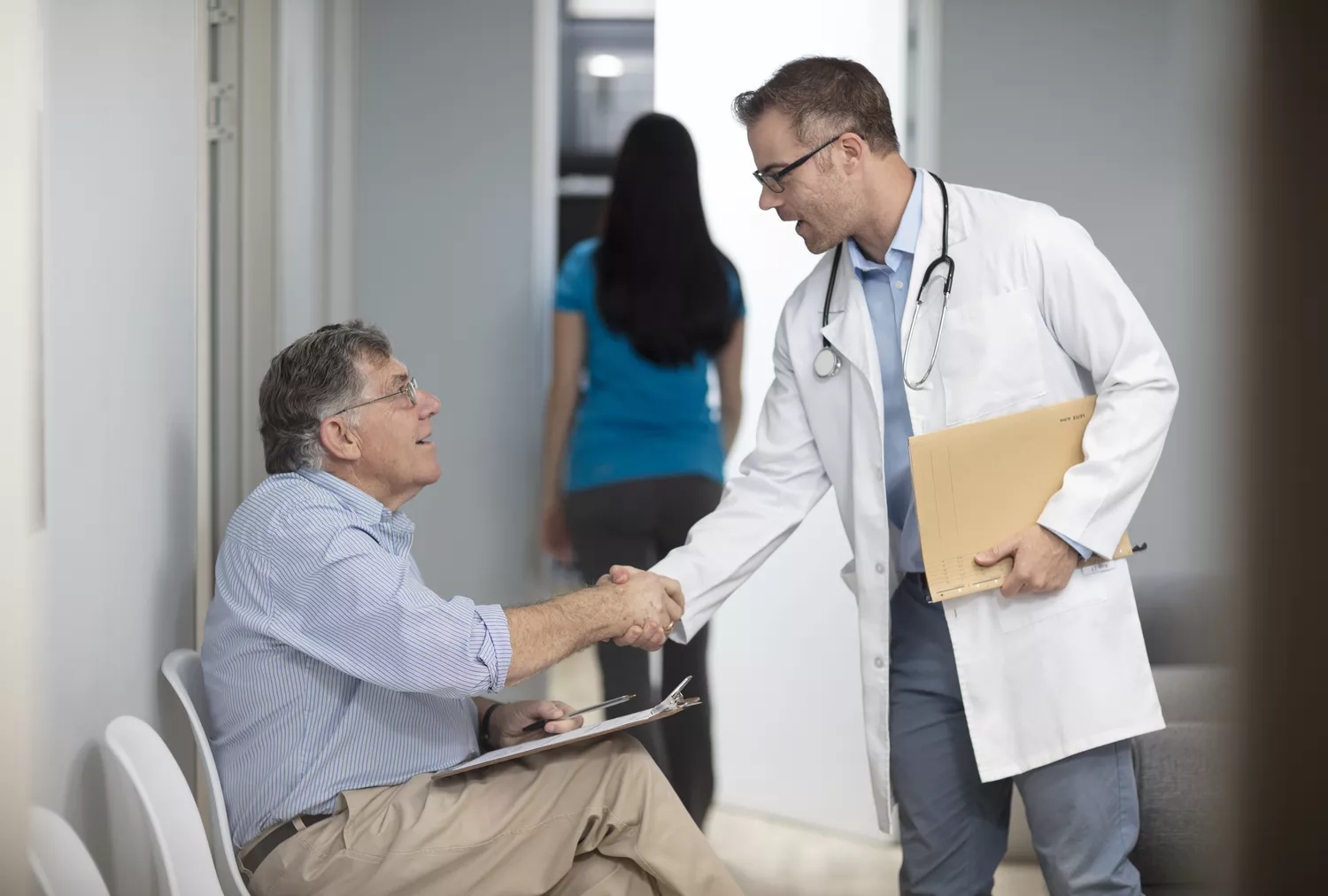 A healthcare professional and a patient reviewing health data on a clipboard in a clinical setting.
