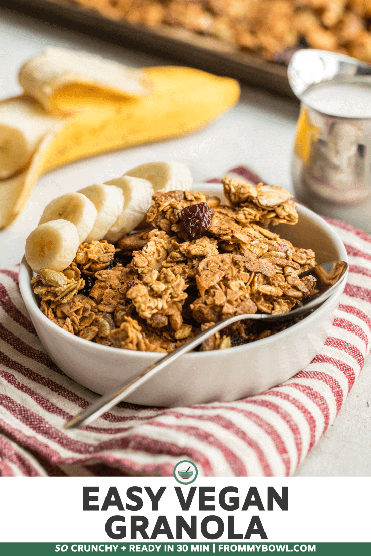 A small white bowl of granola topped with fresh banana slices and a drizzle of granola butter.