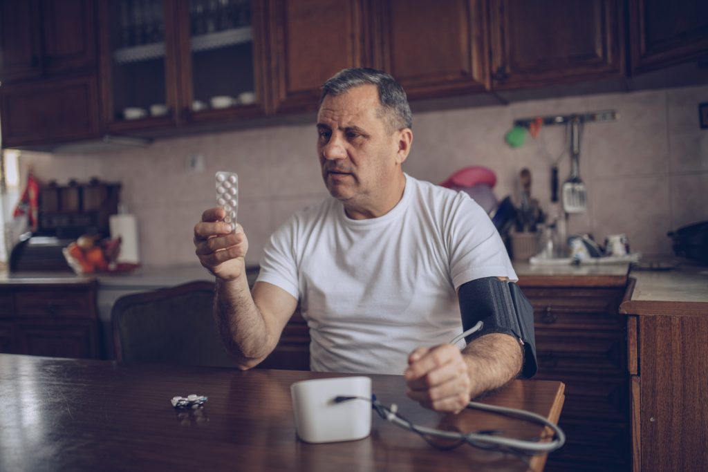 A doctor in a white coat explaining medication and health steps to a patient.