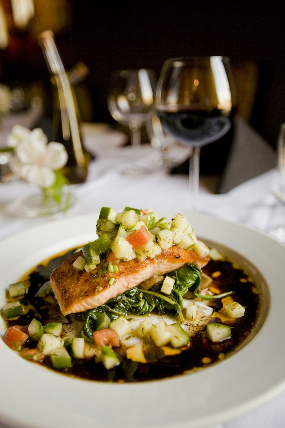 A grilled salmon fillet served with lemon and herbs on a dark plate.