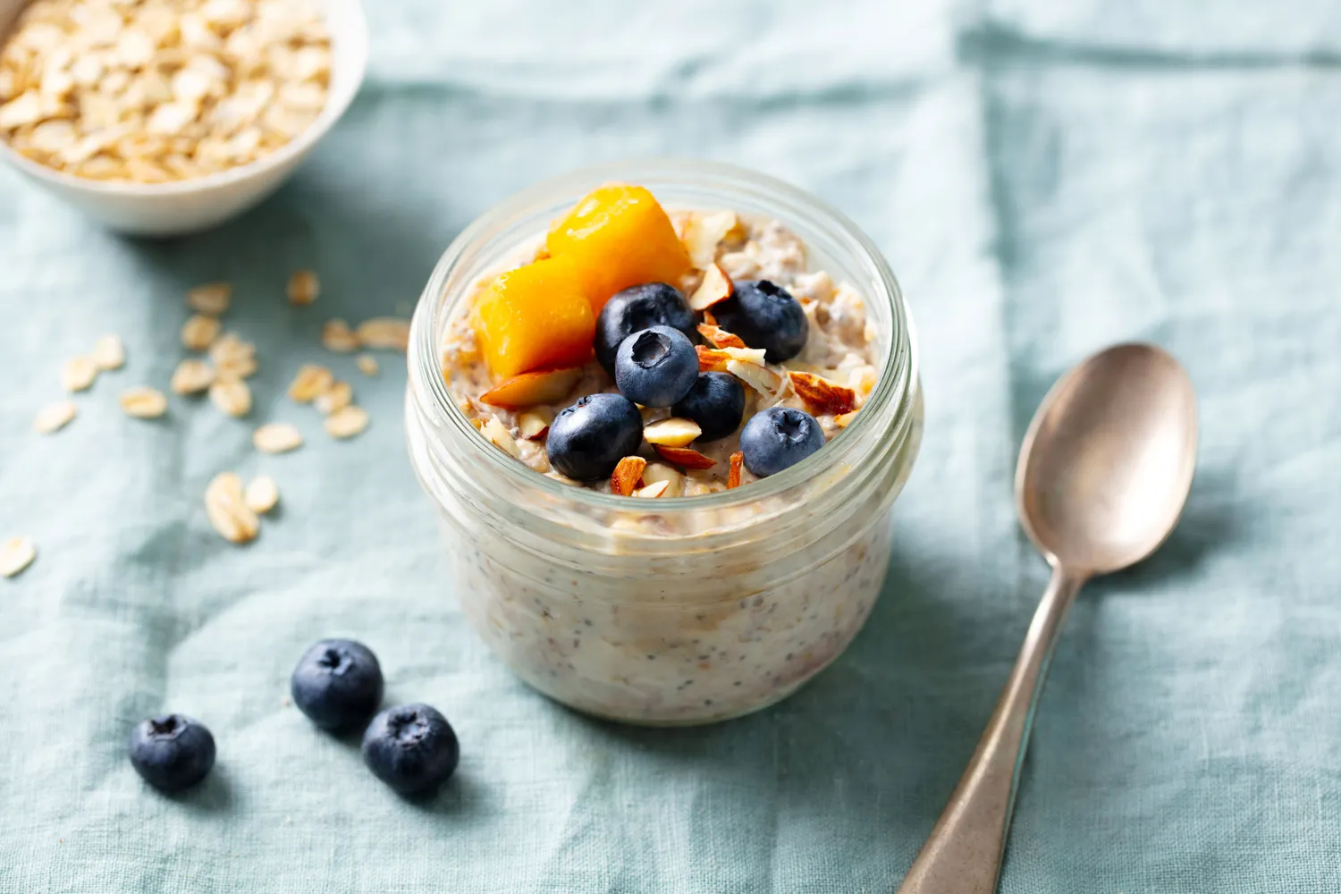 A glass jar of overnight oatmeal with fruit and nuts.