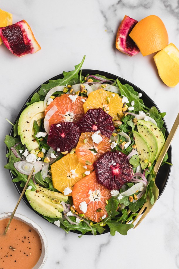 Close-up shot of thin citrus slices paired with fresh arugula.