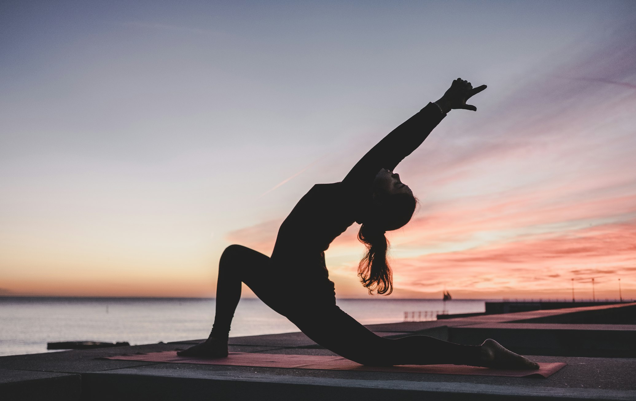A woman in athletic wear lying still on a yoga mat to measure her heart rate.