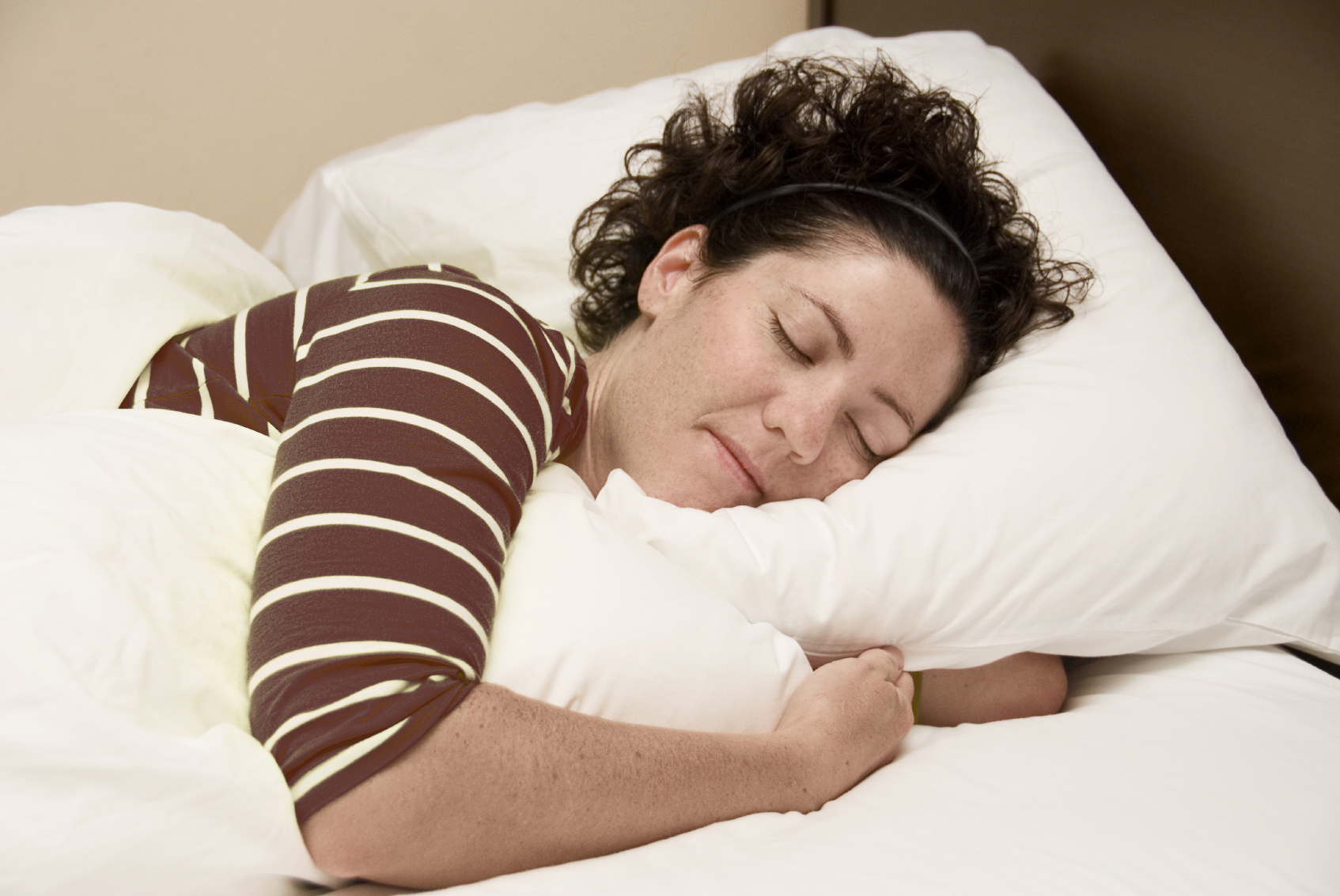A woman sleeping peacefully in a bed with clean white linens.