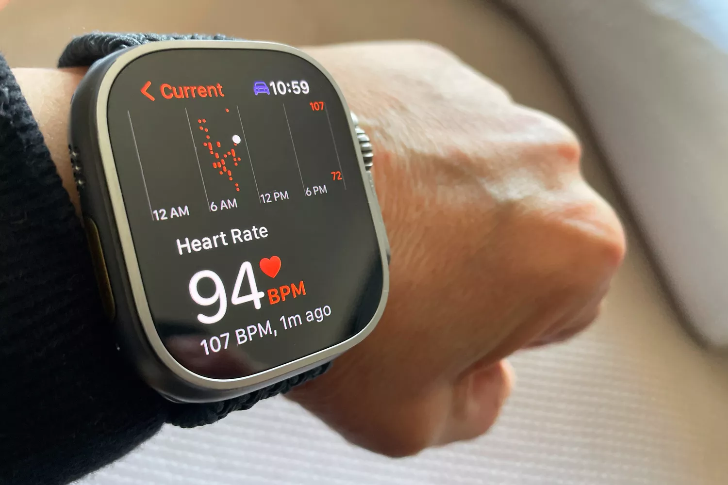 A smartwatch heart rate monitor showing a real-time BPM graph on a person's wrist.