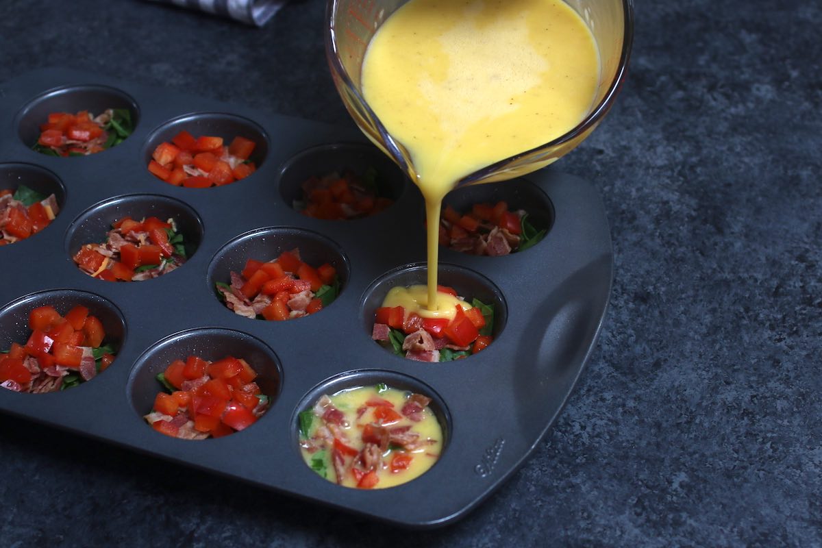 Pouring a whisked egg and yogurt mixture into a prepared muffin pan.