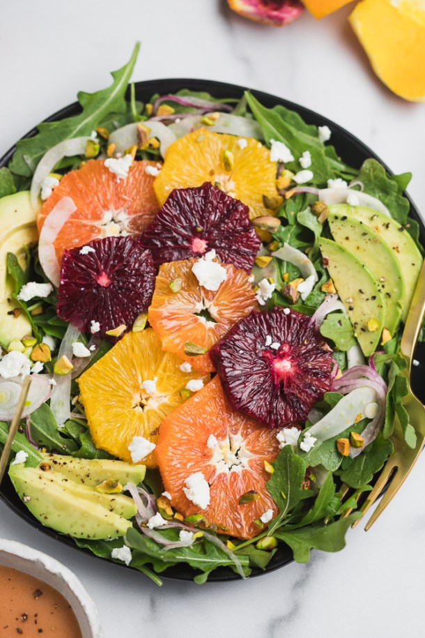 Overhead view of a plated avocado citrus salad featuring vibrant layering.
