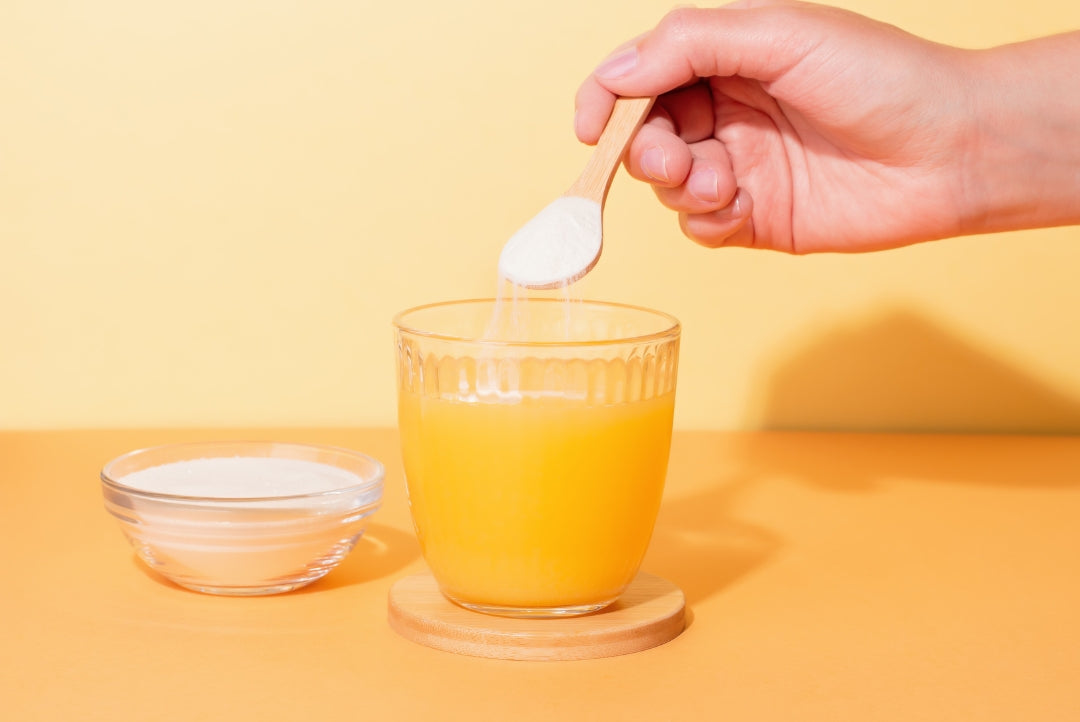 White collagen powder being stirred into a clear glass of water.