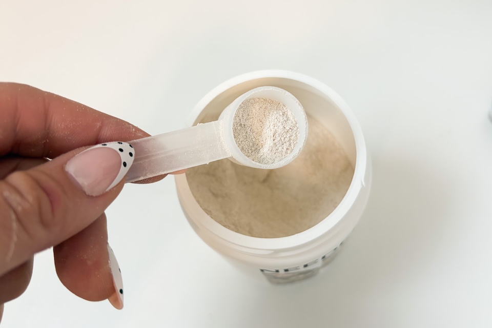 Close-up of a white magnesium powder being measured with a scoop.
