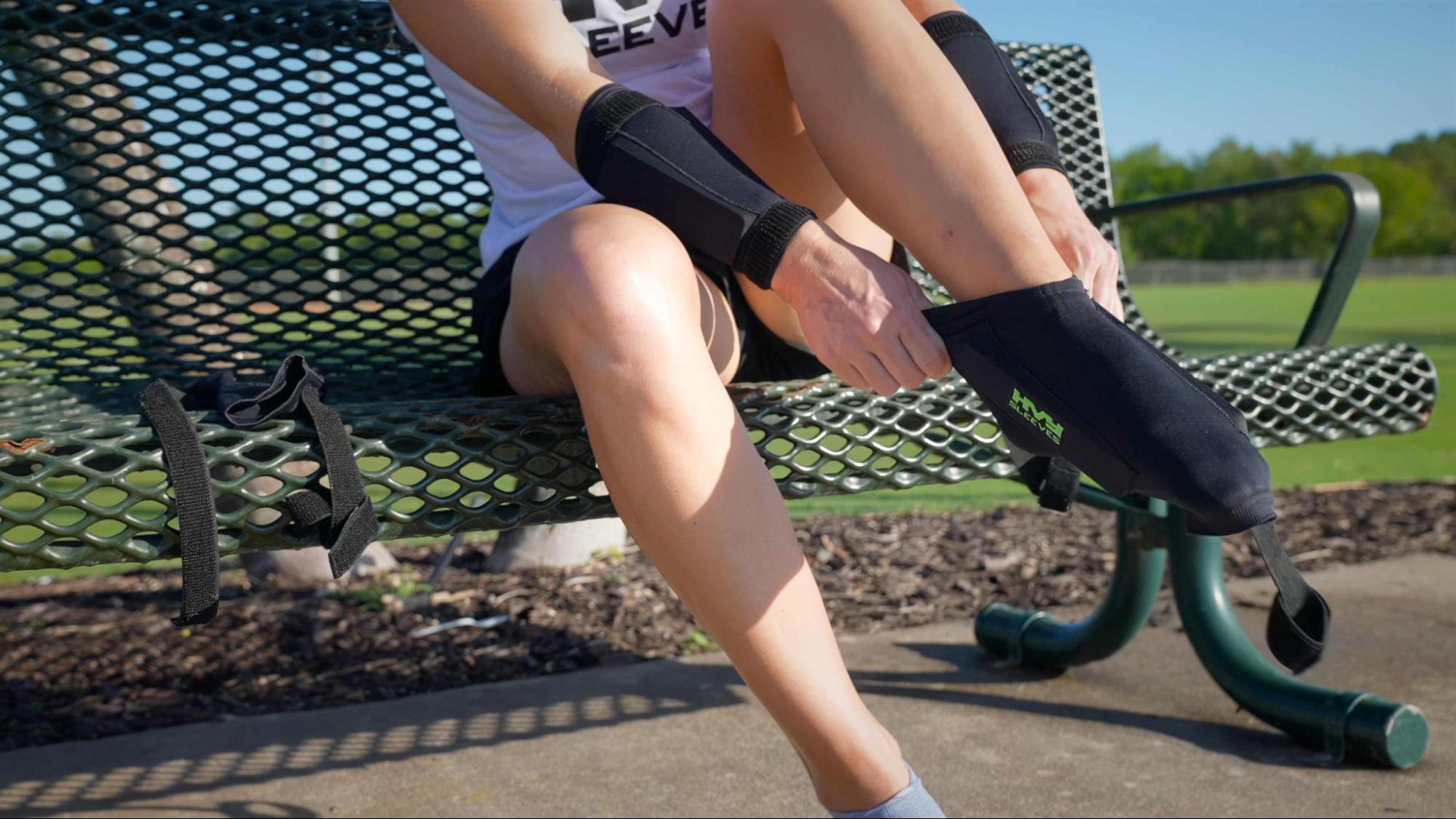 A person sitting on a bench putting on adjustable weighted sleeves