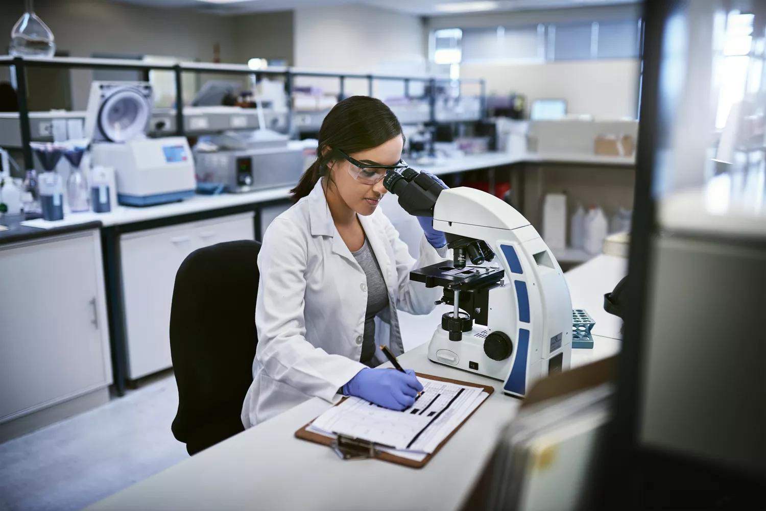 A lab professional in a white coat analyzing a sample, representing clinical diagnostic research.