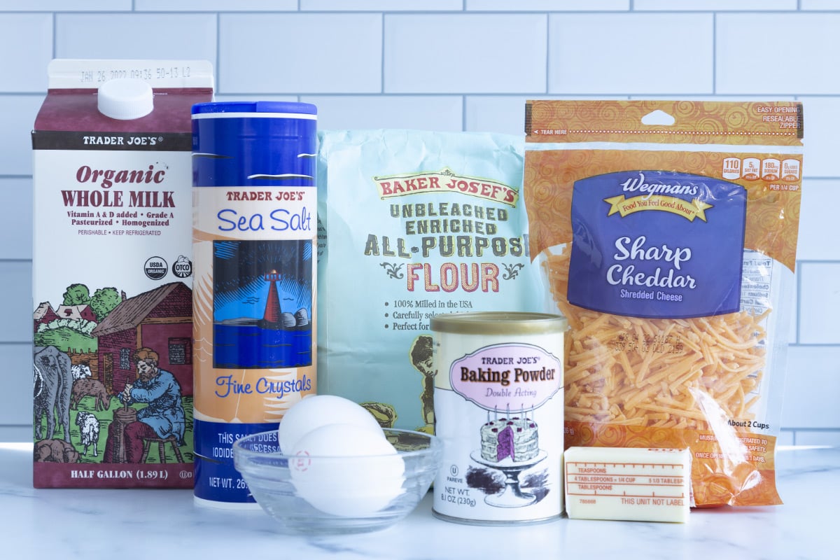 Fresh ingredients for savory waffles including eggs, flour, and dairy on a kitchen counter.