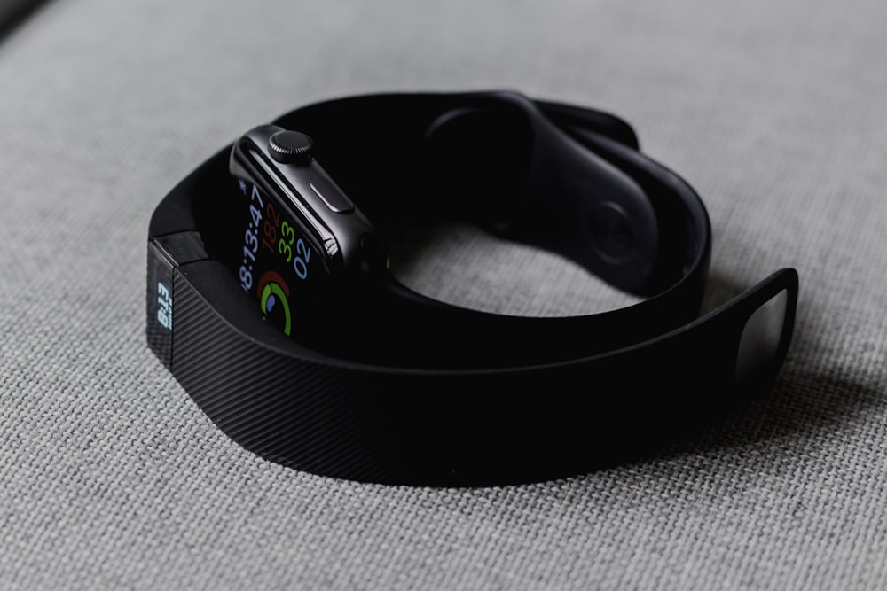 A close-up shot of a woman's wrist wearing a fitness tracker while she walks outdoors.