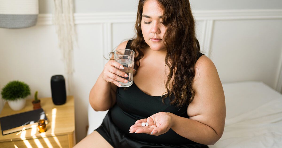 A woman in a domestic setting prepares to take a sleep aid with a glass of water before bed.