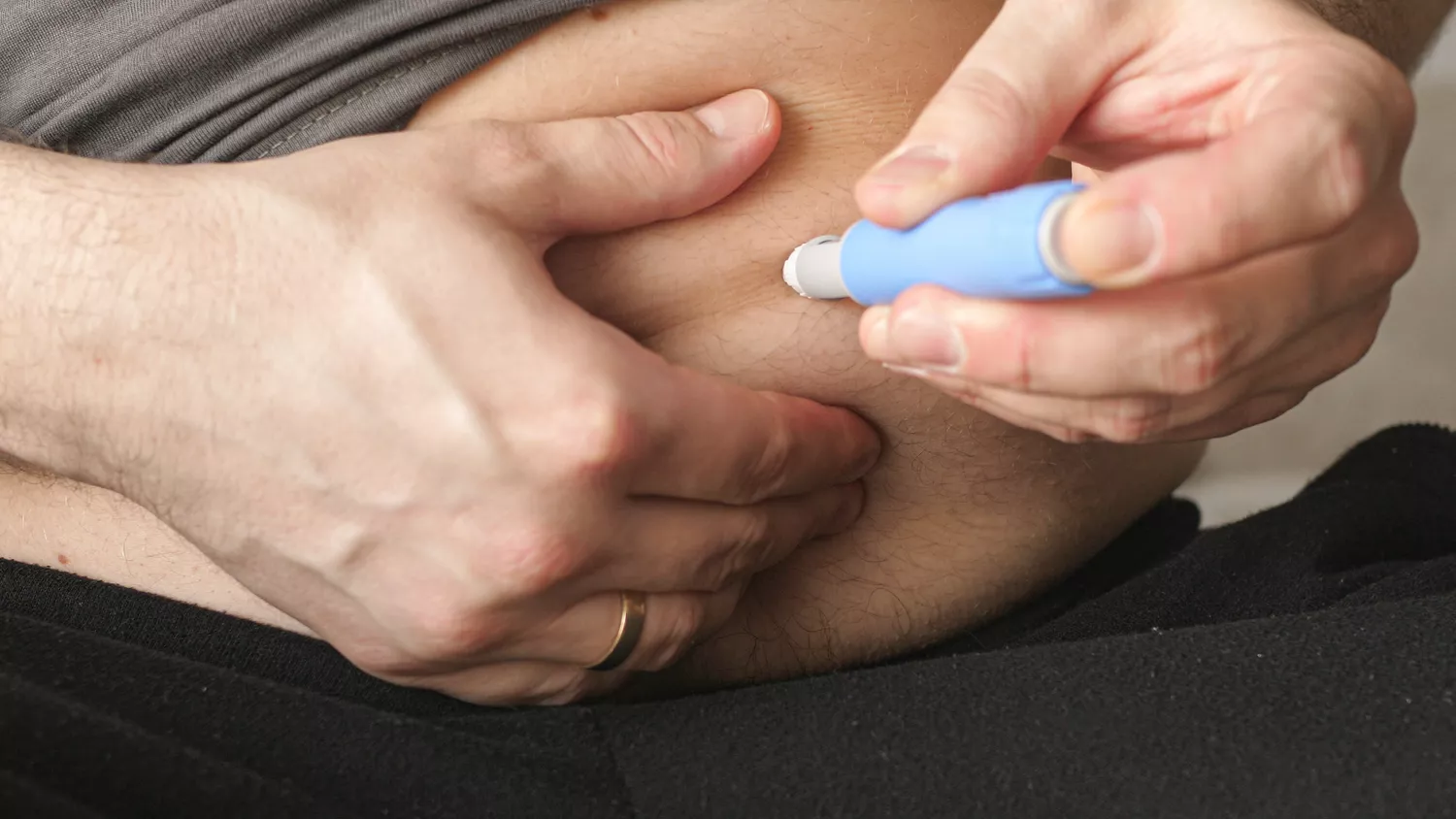 A person administering a semaglutide injection into their abdomen.