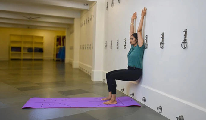 A person holding Chair Pose (Utkatasana) to engage large muscle groups.