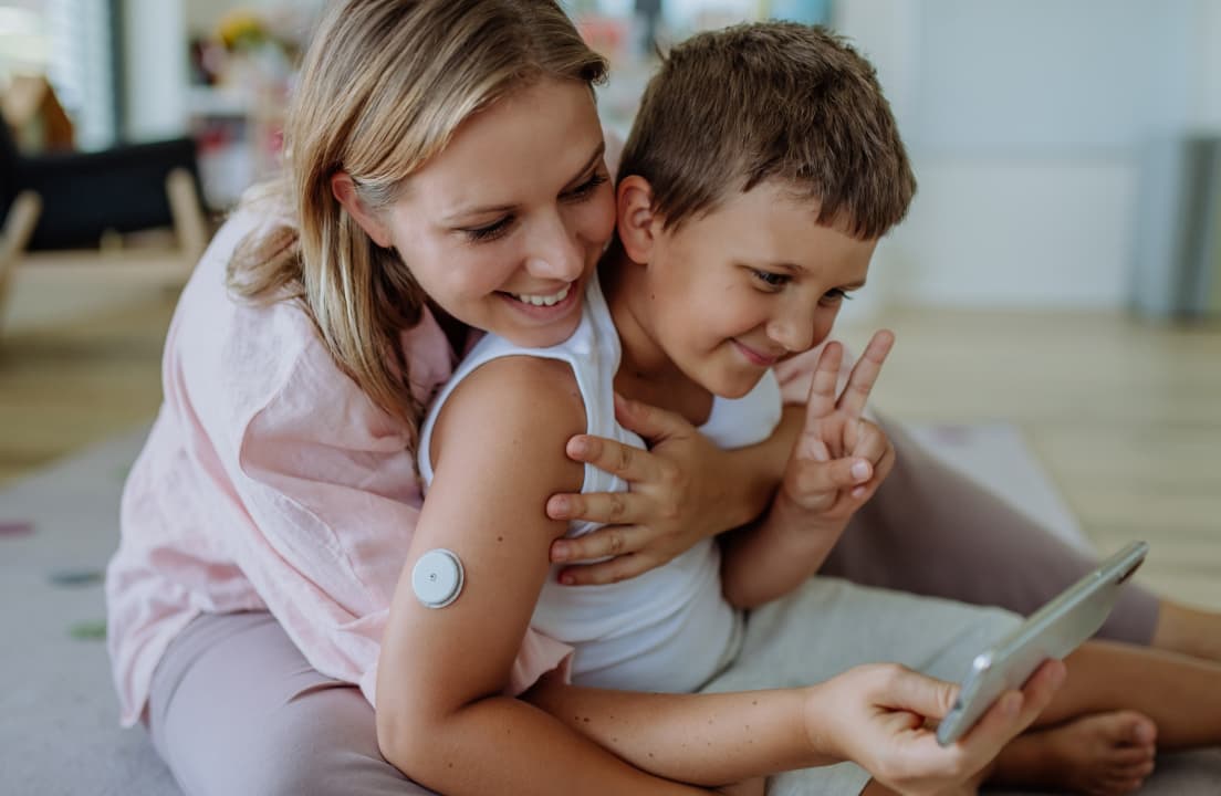A mother and her son looking at a tablet together while wearing diabetes management technology.
