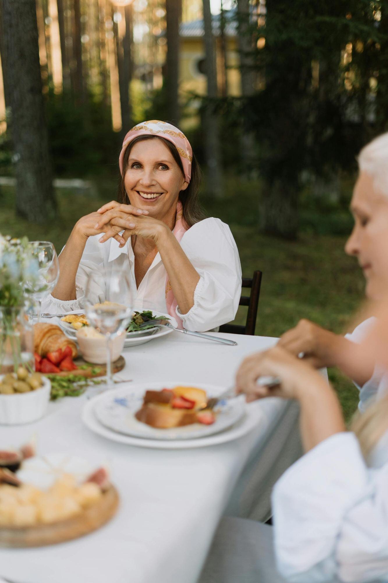 A diverse group of middle-aged women gathering around a dinner table sharing a healthy meal.