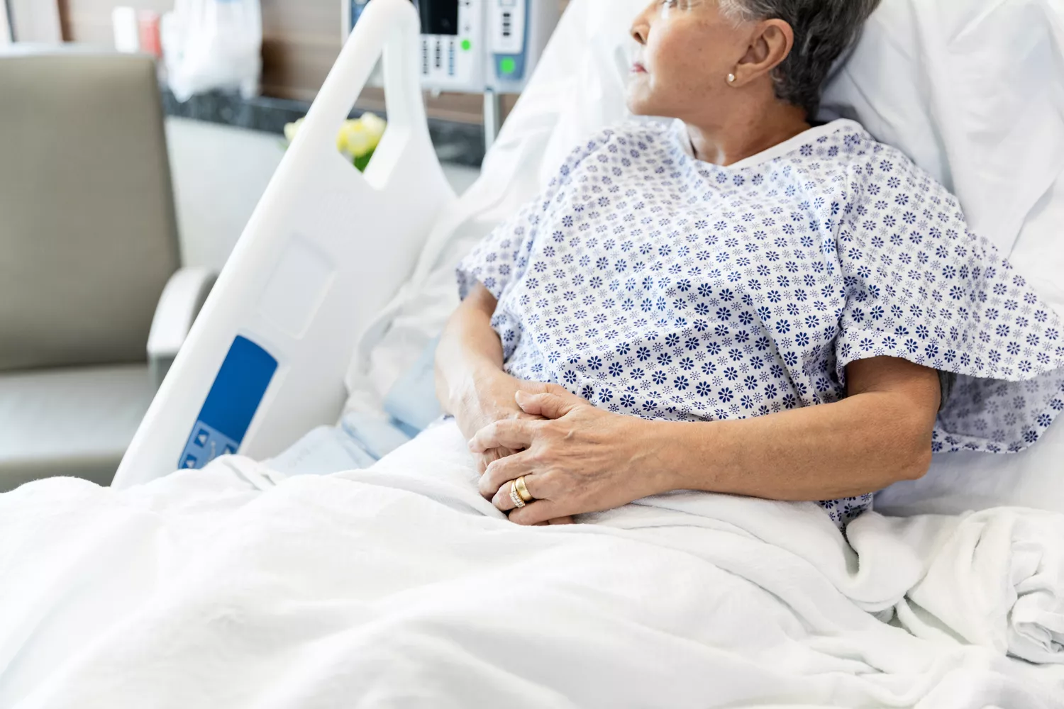 A person lying in a hospital bed, representing the risks of medical complications from incorrect glucose readings.