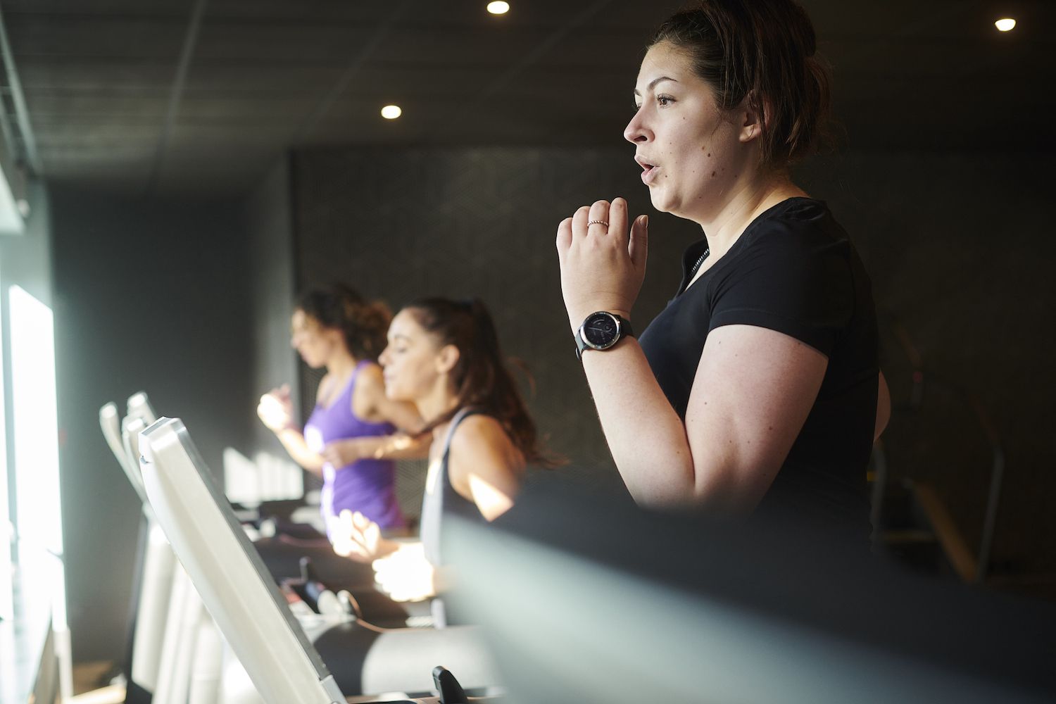 A woman focused on her workout while running on a treadmill in a gym.