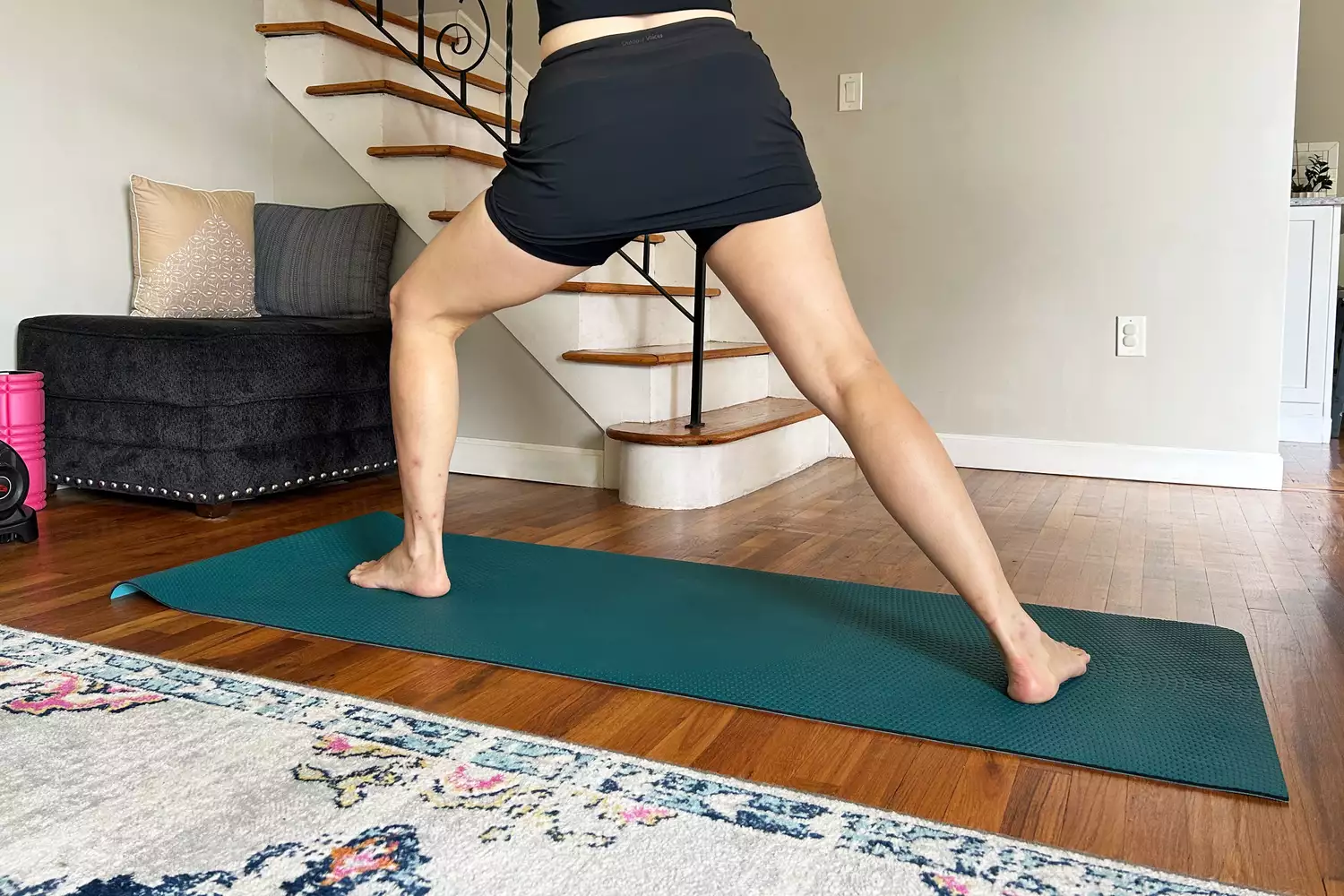 A woman performing a side lunge on a yoga mat while wearing a black athletic skort.