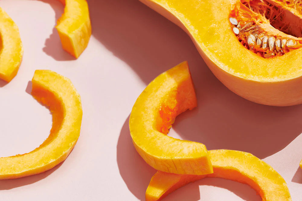 Sliced raw butternut squash arranged on a wooden surface.