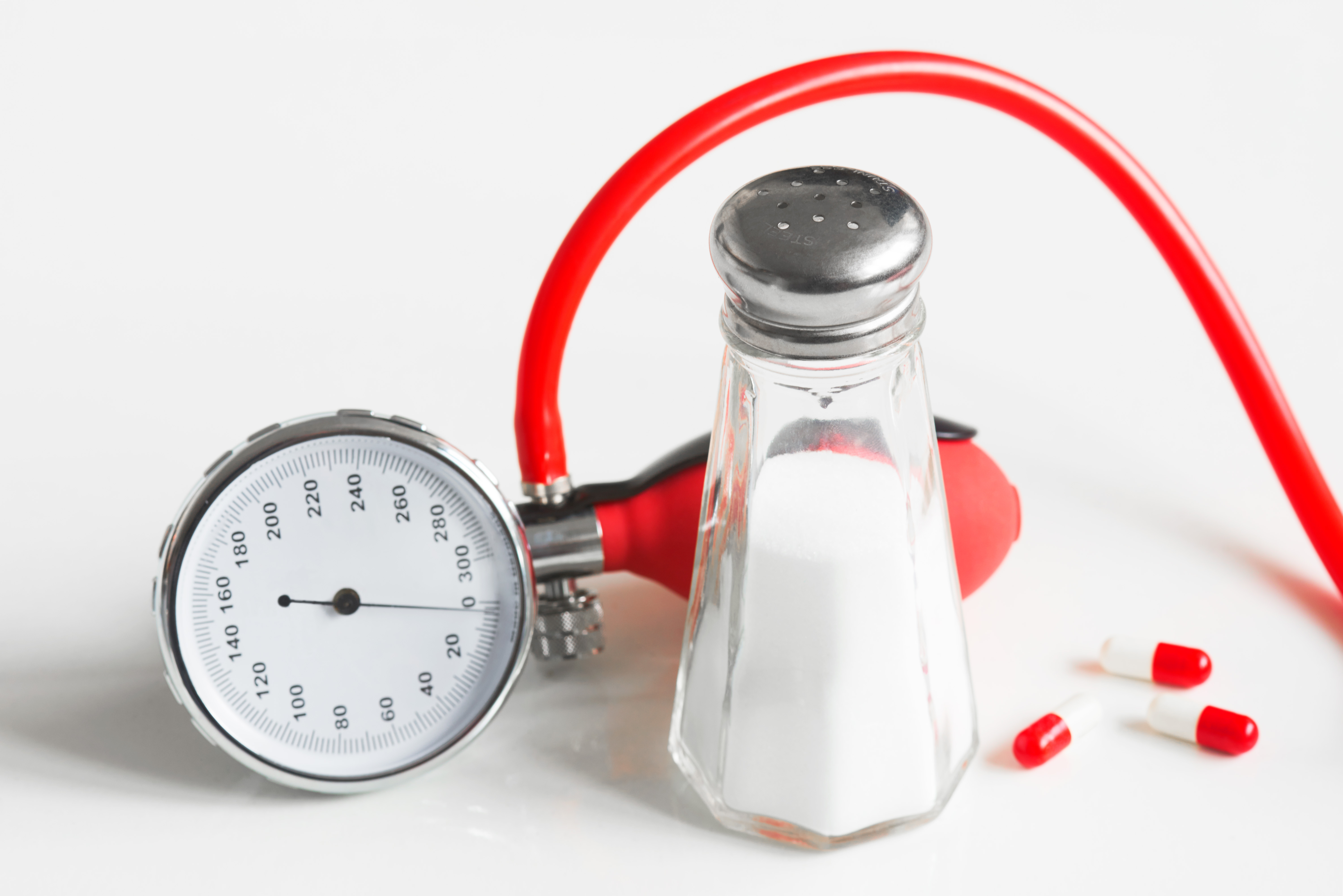 A stethoscope draped over a wooden surface next to a glass salt shaker.
