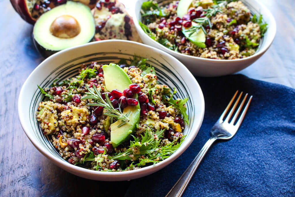 Quinoa salad with pomegranate seeds, avocado slices, and fresh herbs.